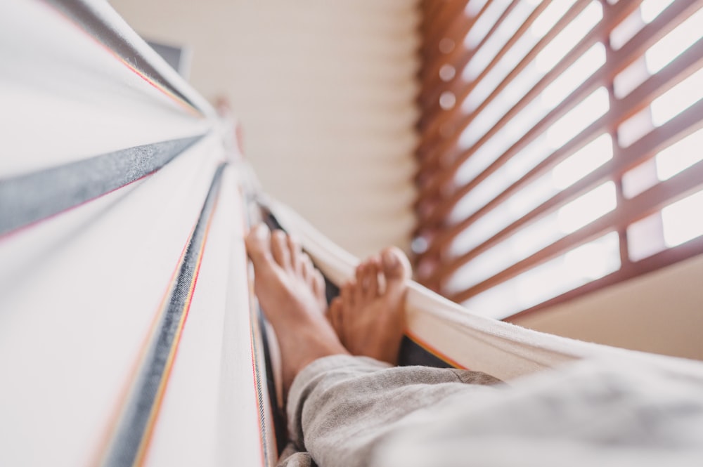 person holding white textile near window blinds