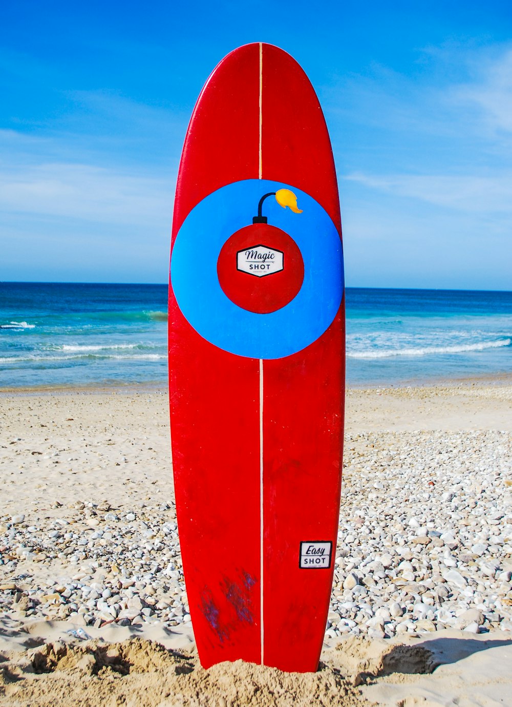 red surfboard on beach shore during daytime