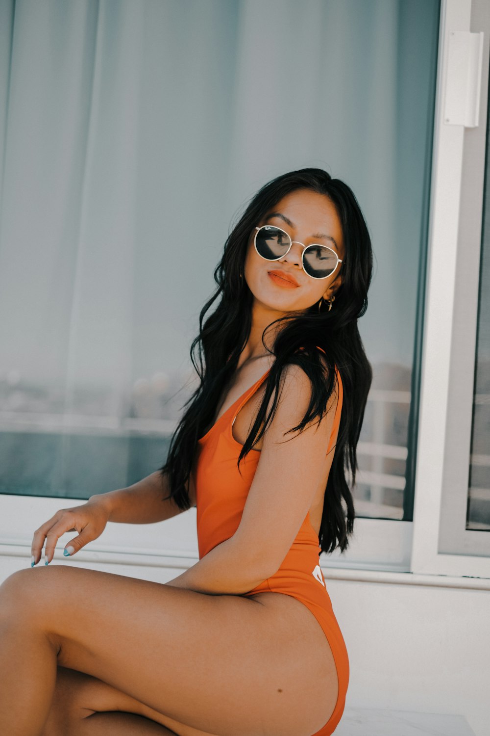 woman in orange tank top and black sunglasses