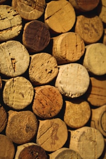 A collection of wine corks tightly arranged together. The corks vary in texture and shade, displaying a range of natural browns and beiges. Each cork shows unique wear patterns and markings from bottle openings.