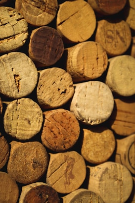 A collection of wine corks tightly arranged together. The corks vary in texture and shade, displaying a range of natural browns and beiges. Each cork shows unique wear patterns and markings from bottle openings.