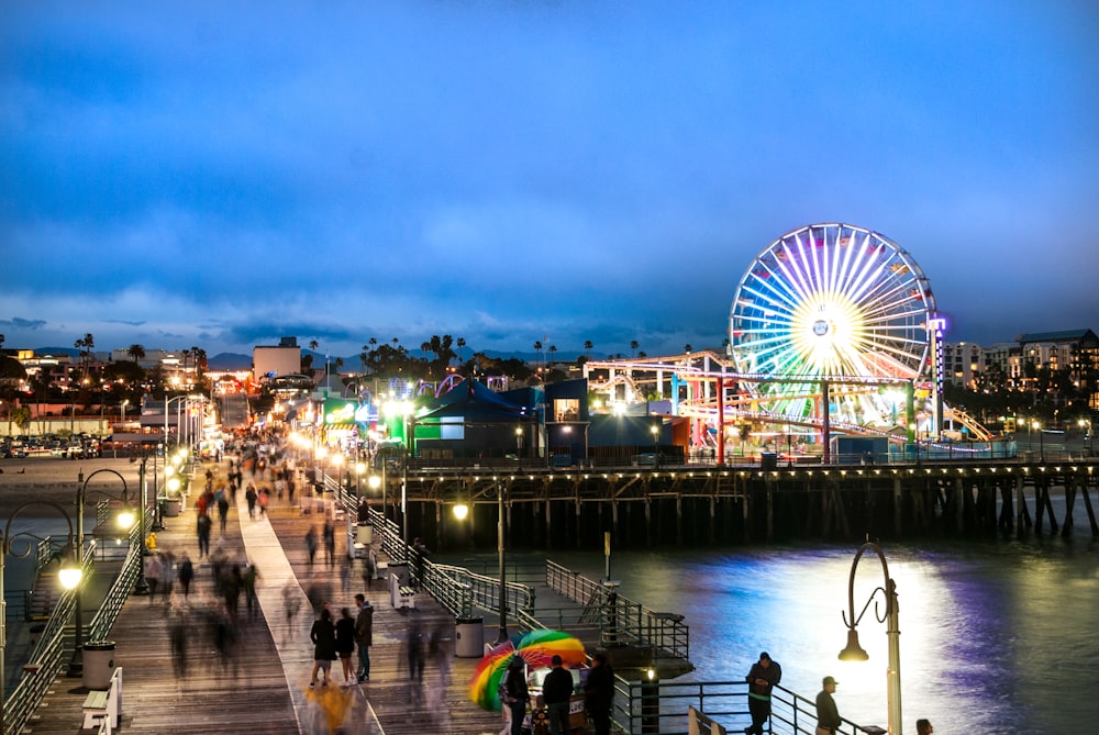 people walking on sidewalk near body of water during night time