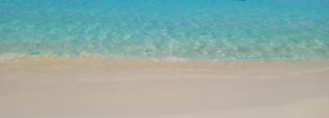 Crystal-clear turquoise waters gently lapping against a pristine sandy beach.