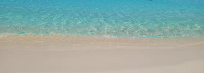 Serene turquoise waters lapping gently against a quiet sandy beach.