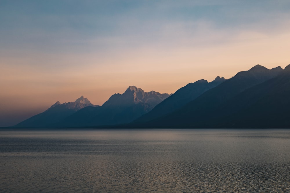 body of water near mountain during daytime