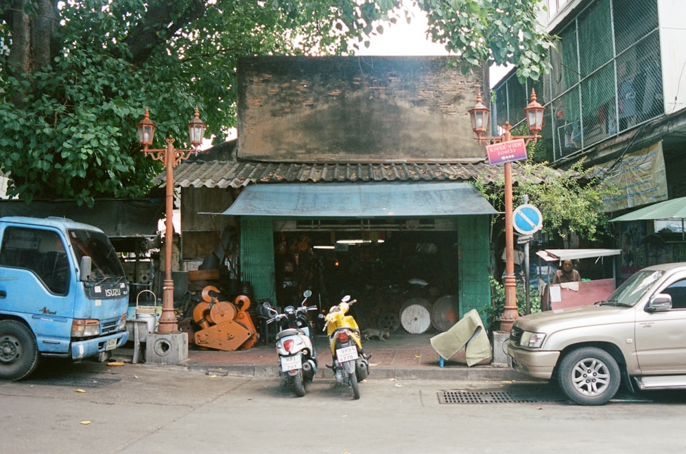 white and orange motor scooter parked beside gray concrete building during daytime