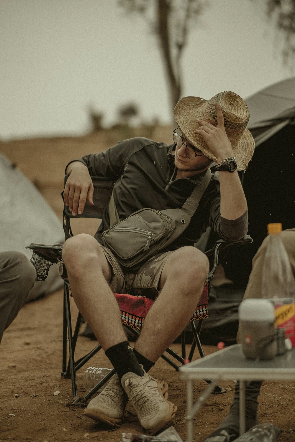 man in brown jacket sitting on red and black camping chair