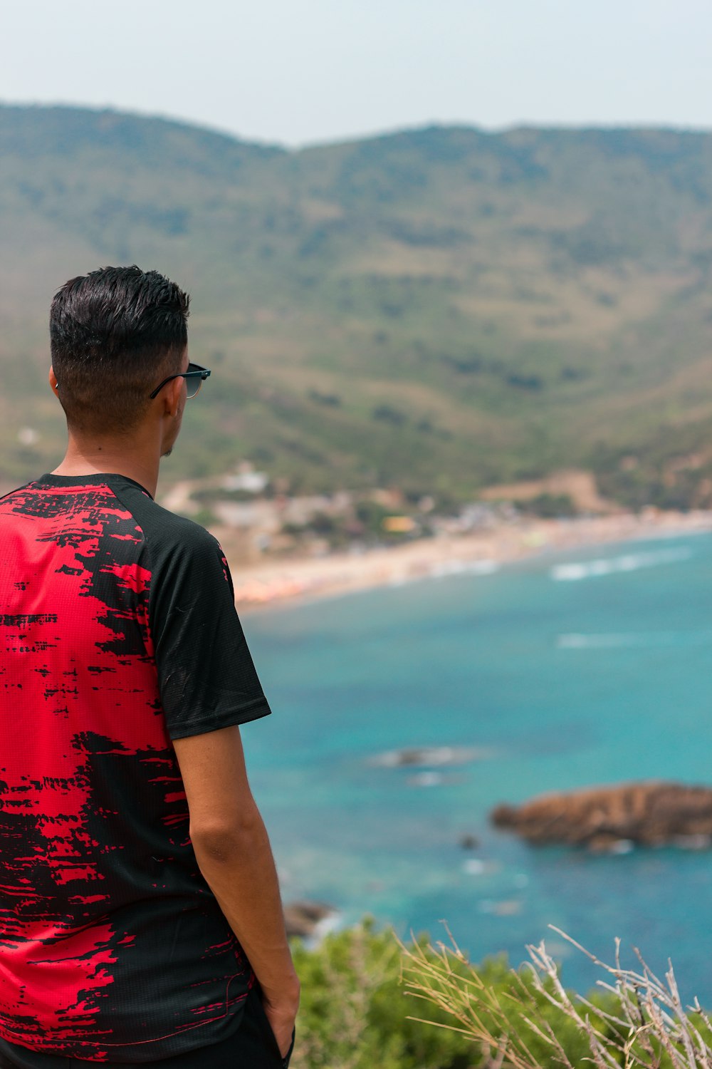 man in red and black crew neck t-shirt standing near body of water during daytime