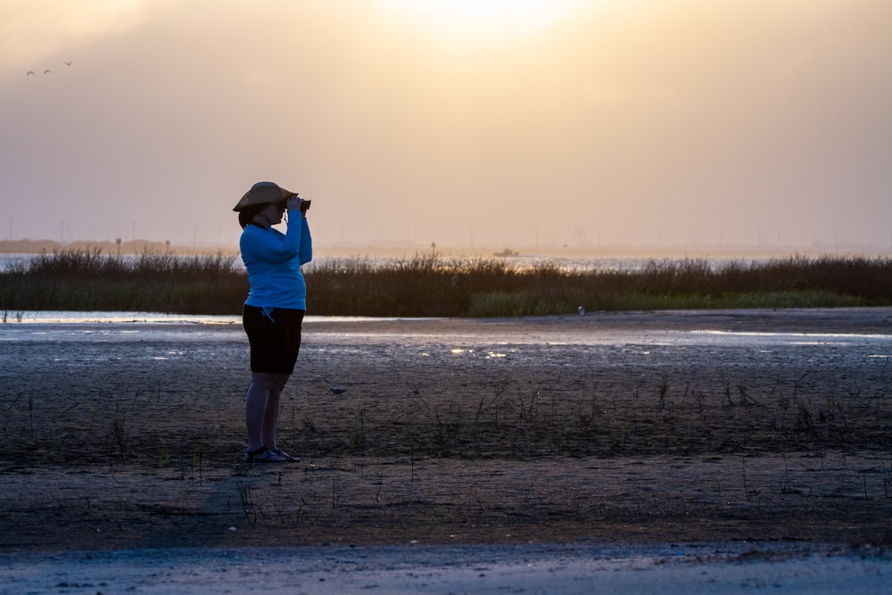 woman in white shirt and black pants standing on wet sand during daytime