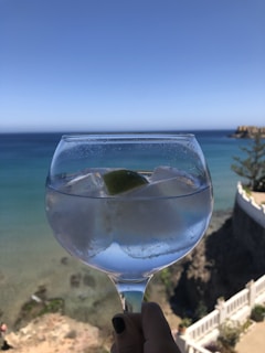 Close-up of hands holding a cold drink, waves gently rocking the yacht in the background.