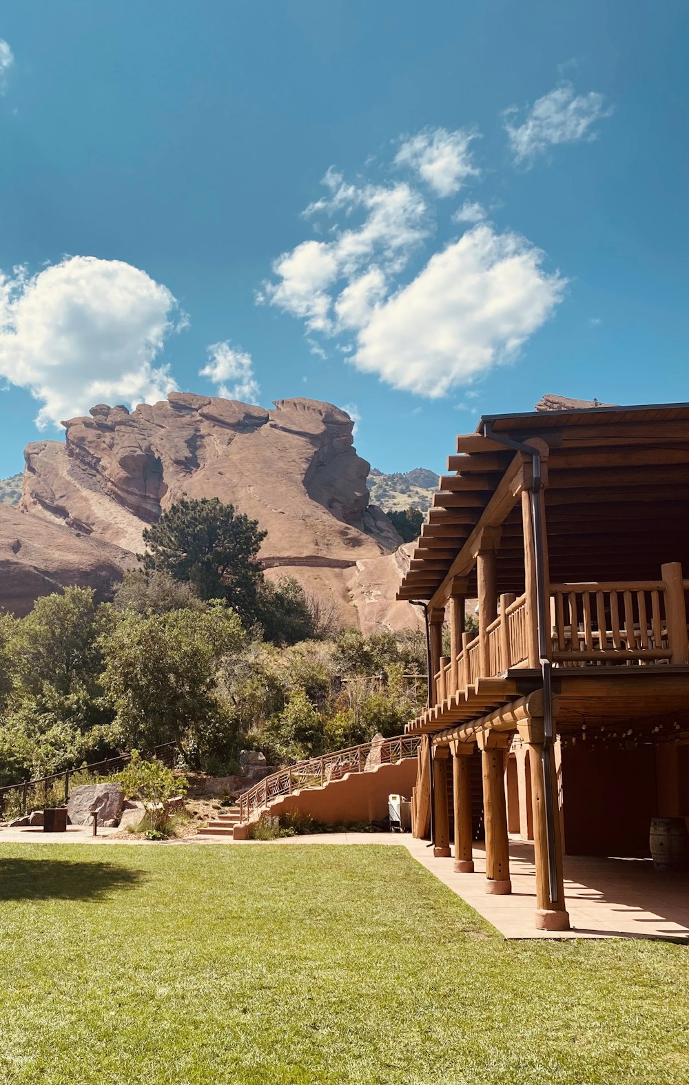 brown wooden house near green trees and brown mountain under blue sky during daytime