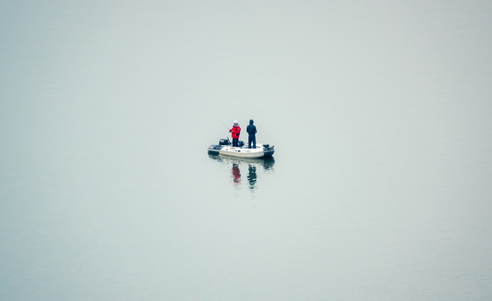 2 person riding on white boat on body of water