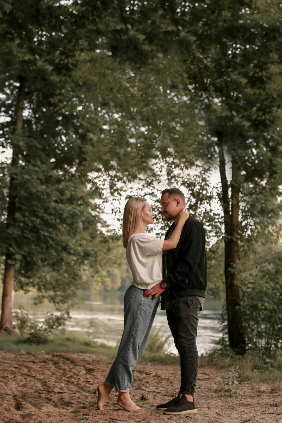 man and woman kissing on pathway between trees during daytime