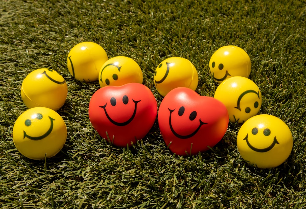emoji sorridente vermelho e amarelo na grama verde