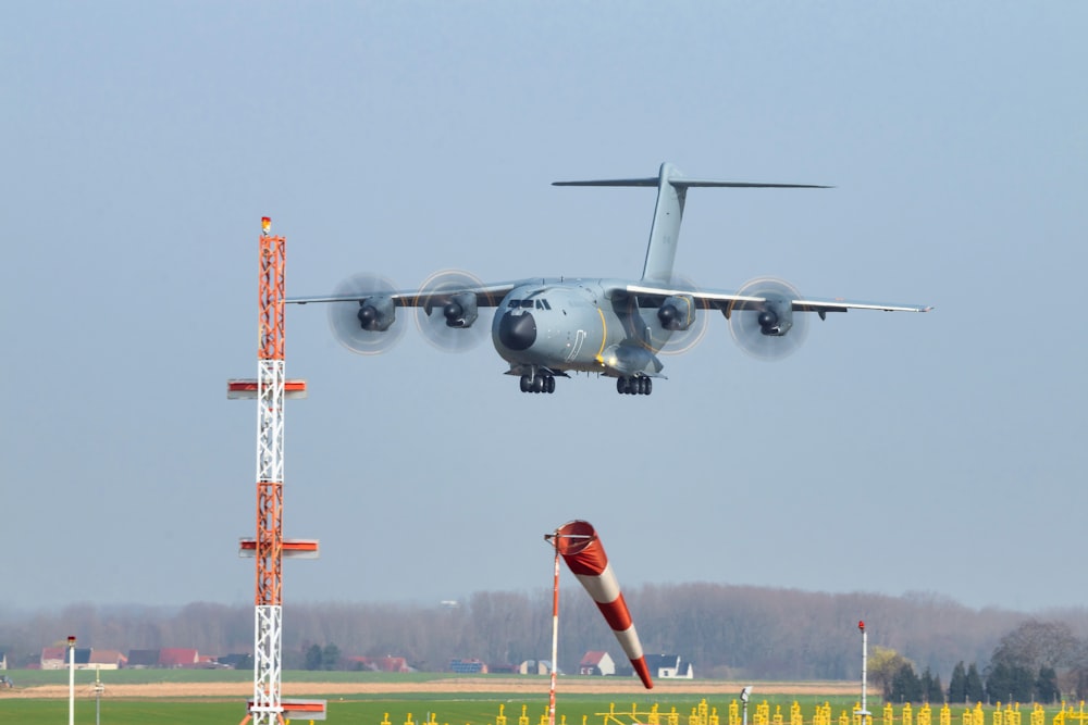 Avión a reacción gris y rojo volando sobre un campo de hierba verde durante el día