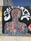 A mural depicting numerous raised fists in various skin tones, symbolizing unity and strength. The word 'Solidarity' is painted in large, stylized letters above the fists, conveying a message of togetherness and support.