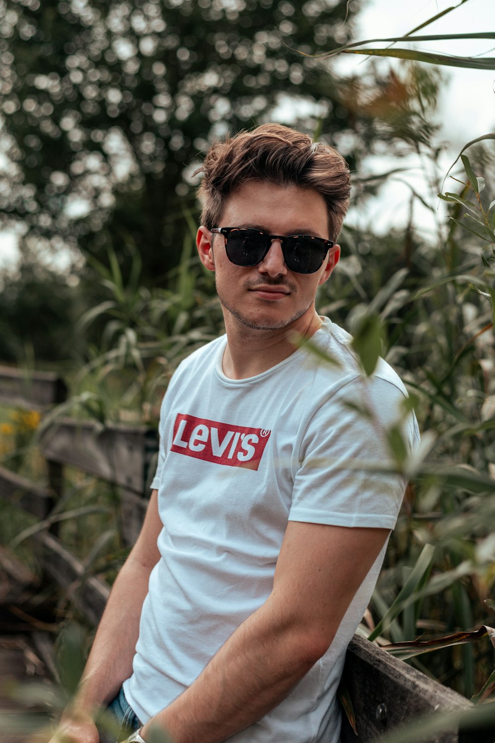 Homme en T-shirt blanc à col rond portant des lunettes de soleil noires