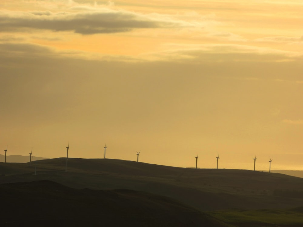 wind turbines on green grass field under white clouds