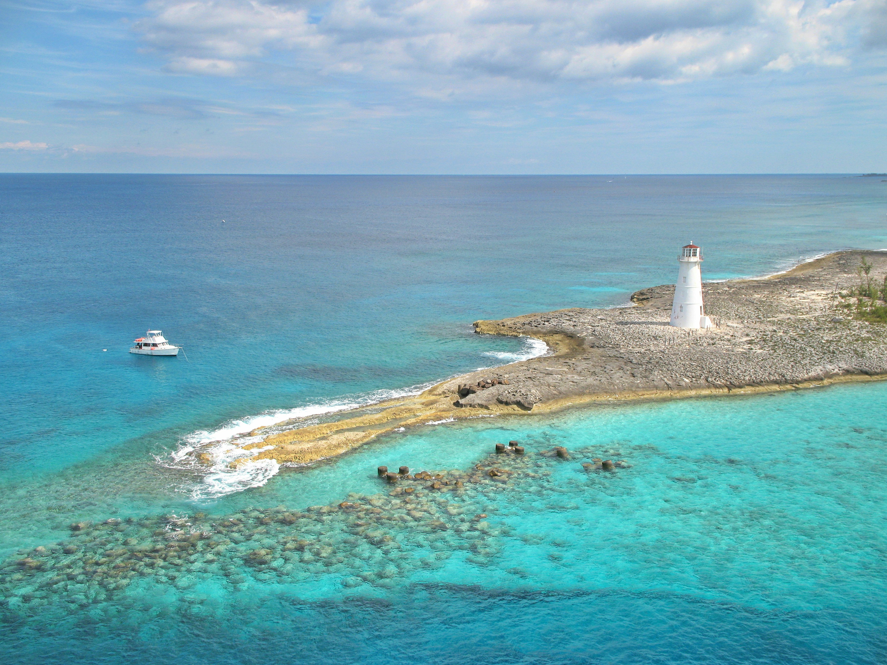 white lighthouse on brown sand near body of water during daytime