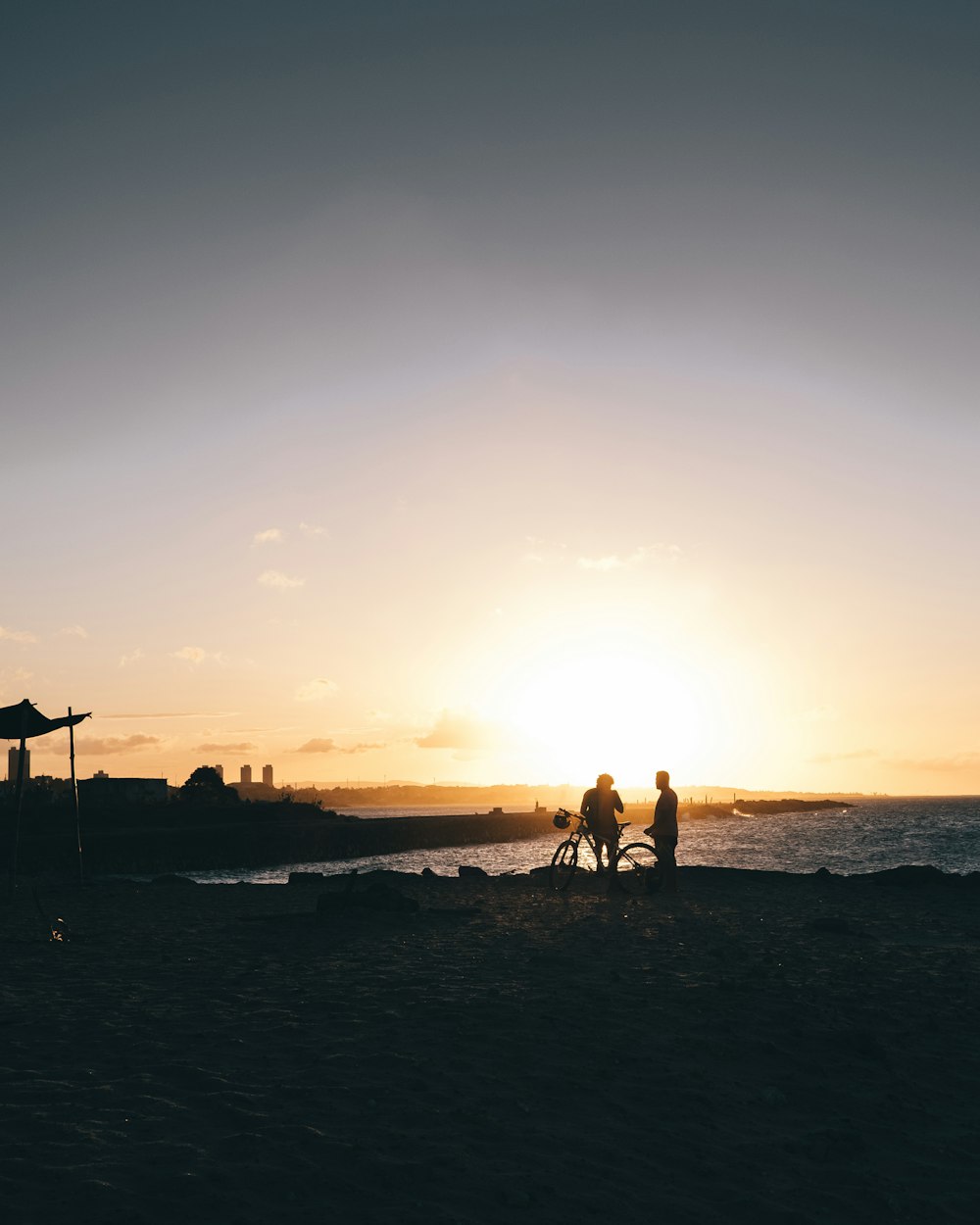 Silueta de personas que caminan en la playa durante la puesta del sol