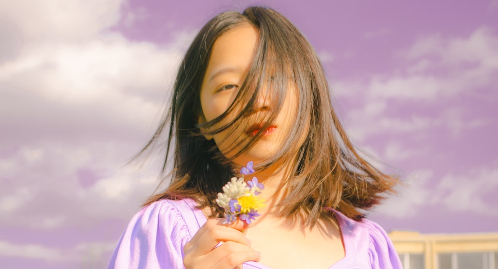 woman in pink and white shirt holding white flower