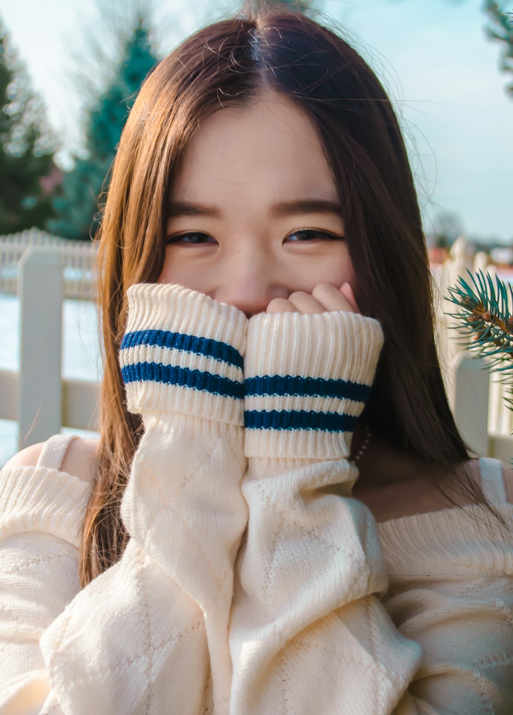 girl in white sweater covering her face with her hands