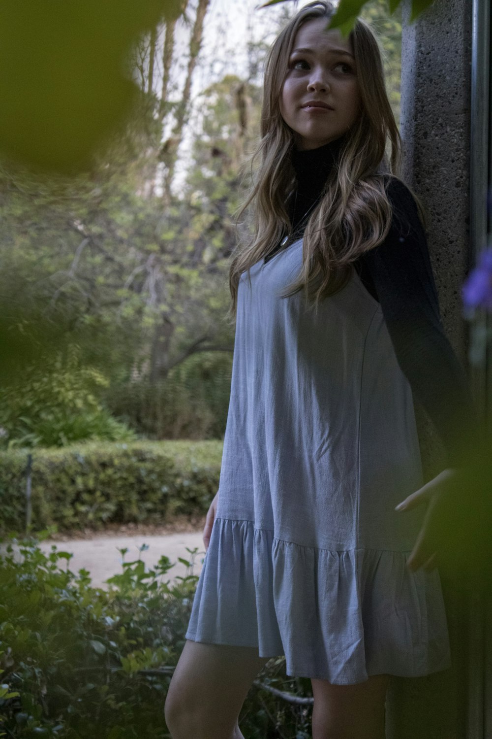 woman in blue long sleeve dress standing near green trees during daytime