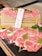 Slices of marbled Wagyu beef are elegantly arranged on a wooden mat, garnished with fresh greens and pink flowers. A small wooden sign written in Japanese and English identifies the meat as A5 grade Wagyu. The setup is enhanced by a dark stone surface, providing a contrast to the vibrant colors of the beef.