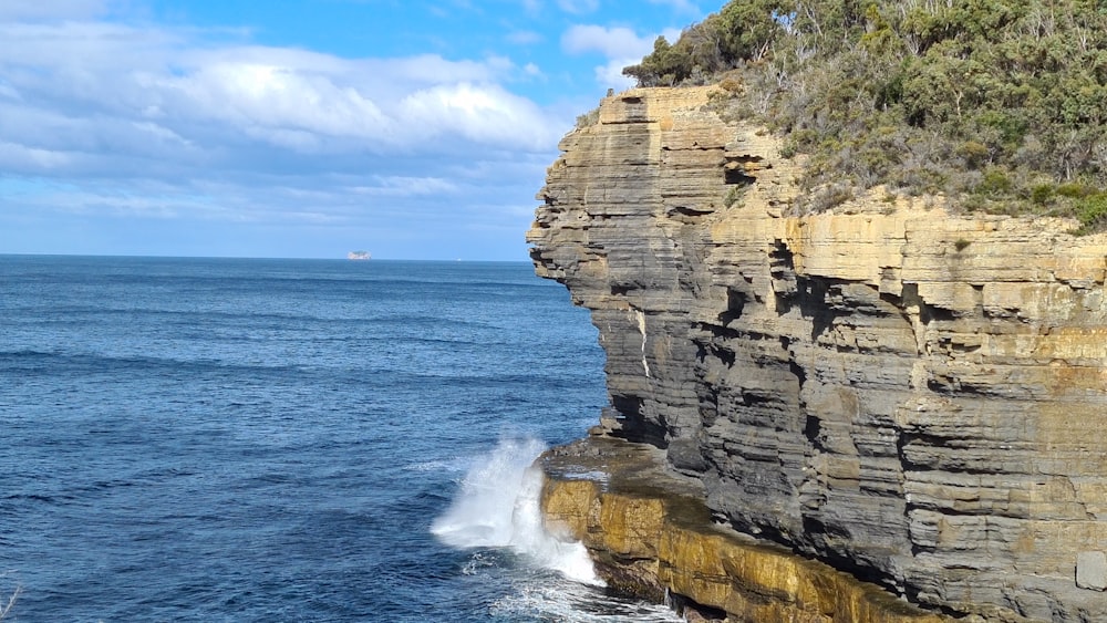 brown rocky mountain beside sea under blue sky during daytime