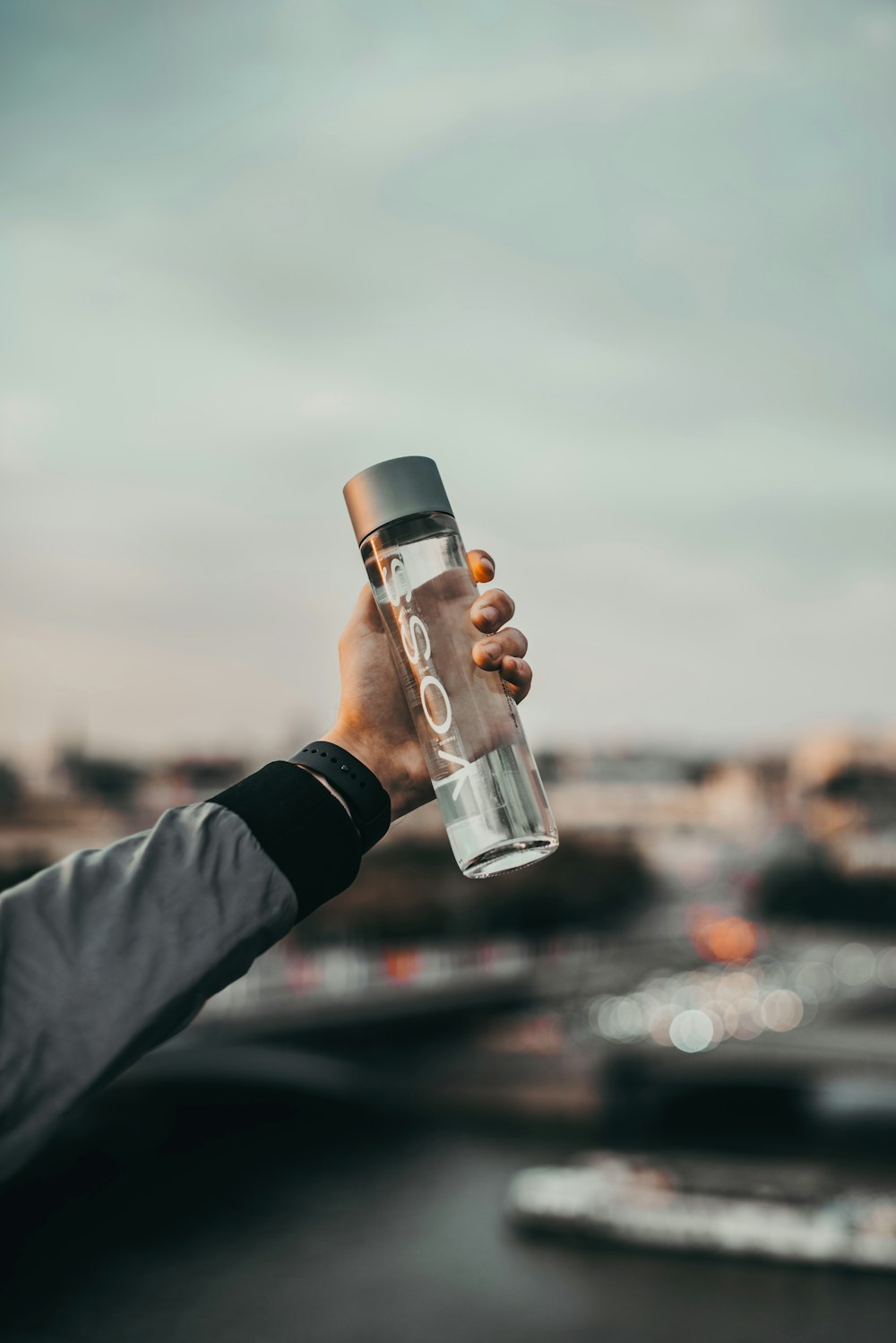 personne tenant une bouteille en verre transparent