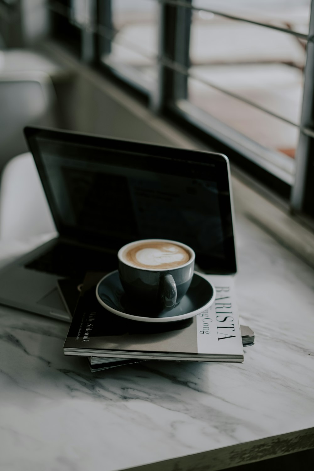 white ceramic mug on black and white book