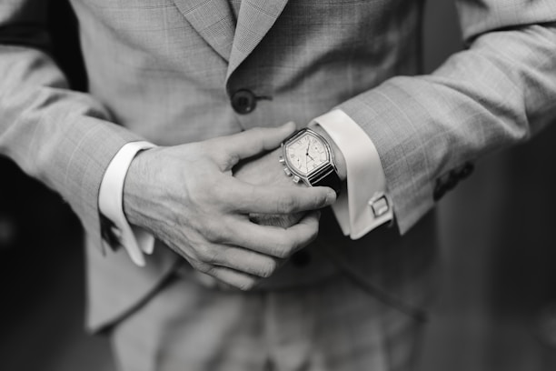 A stylish man wearing a 42mm men's watch while adjusting his cufflink in natural light.