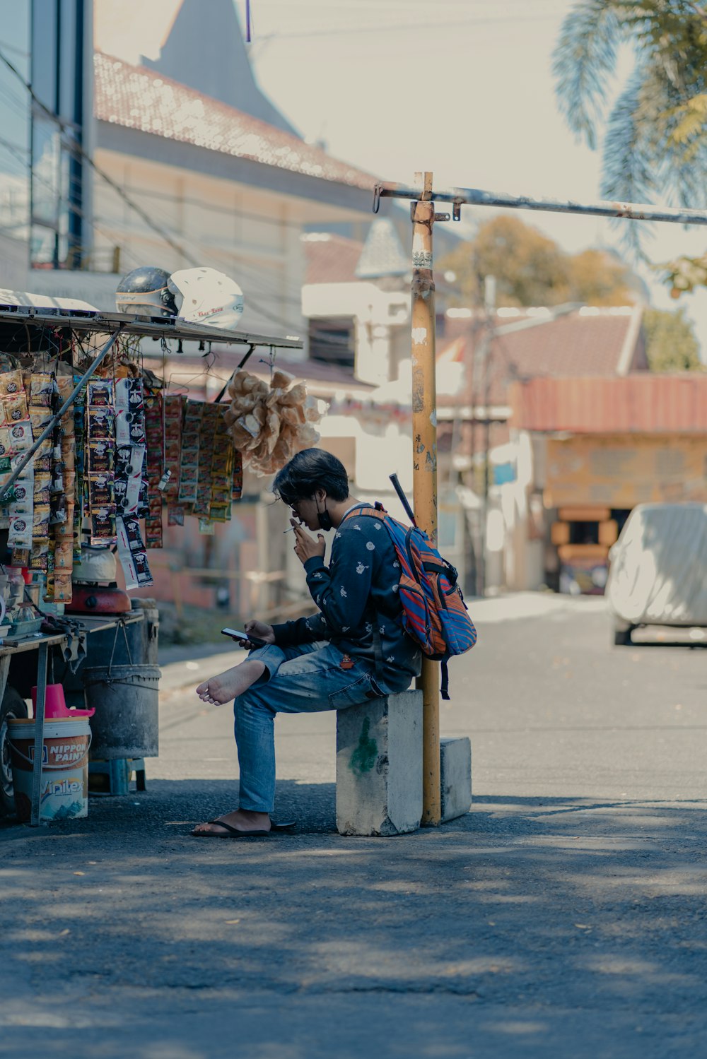 man in blue and red jacket sitting on gray concrete bench during daytime