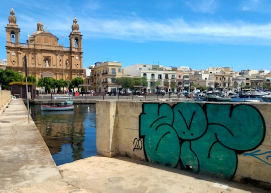 green metal fence near body of water during daytime in Msida Parish Church Malta