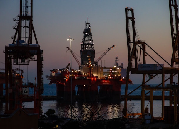 Oil rig platform at sunset with engineers inspecting equipment.