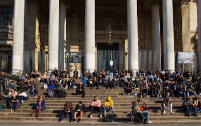 people sitting on bench near building during daytime melting pot zoom background