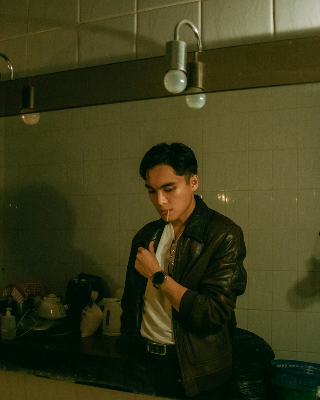 man in black leather jacket standing near white wall