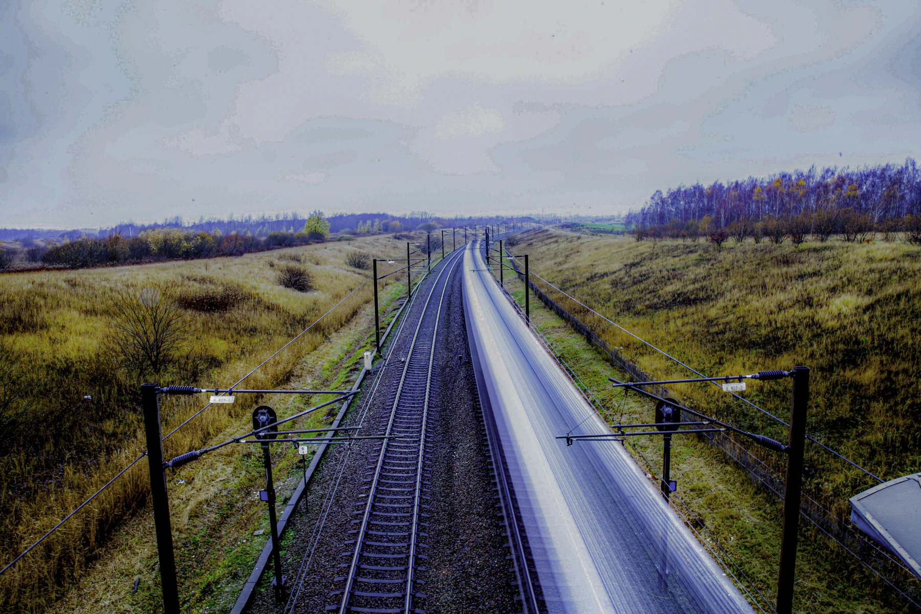 Parallel railway tracks run through open land near Copenhagen.