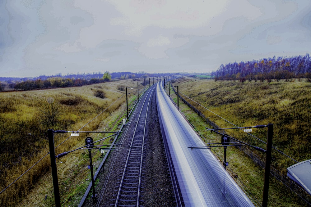 gray train rail near green grass field during daytime