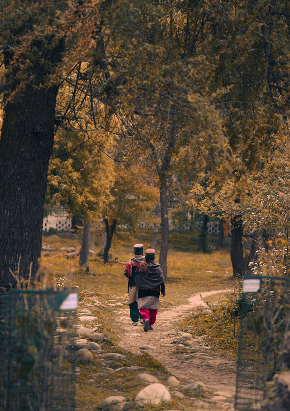 man in brown jacket and black pants walking on pathway