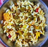 A bowl filled with a mixture of puffed rice, lentils, spices, and assorted savory items is displayed, showcasing a colorful and textured assortment of a traditional Indian snack.