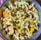 A bowl filled with a mixture of puffed rice, lentils, spices, and assorted savory items is displayed, showcasing a colorful and textured assortment of a traditional Indian snack.