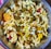 A bowl filled with a mixture of puffed rice, lentils, spices, and assorted savory items is displayed, showcasing a colorful and textured assortment of a traditional Indian snack.