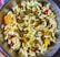 A bowl filled with a mixture of puffed rice, lentils, spices, and assorted savory items is displayed, showcasing a colorful and textured assortment of a traditional Indian snack.