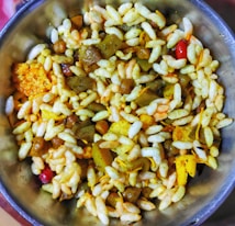 A bowl filled with a mixture of puffed rice, lentils, spices, and assorted savory items is displayed, showcasing a colorful and textured assortment of a traditional Indian snack.