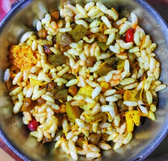 A bowl filled with a mixture of puffed rice, lentils, spices, and assorted savory items is displayed, showcasing a colorful and textured assortment of a traditional Indian snack.