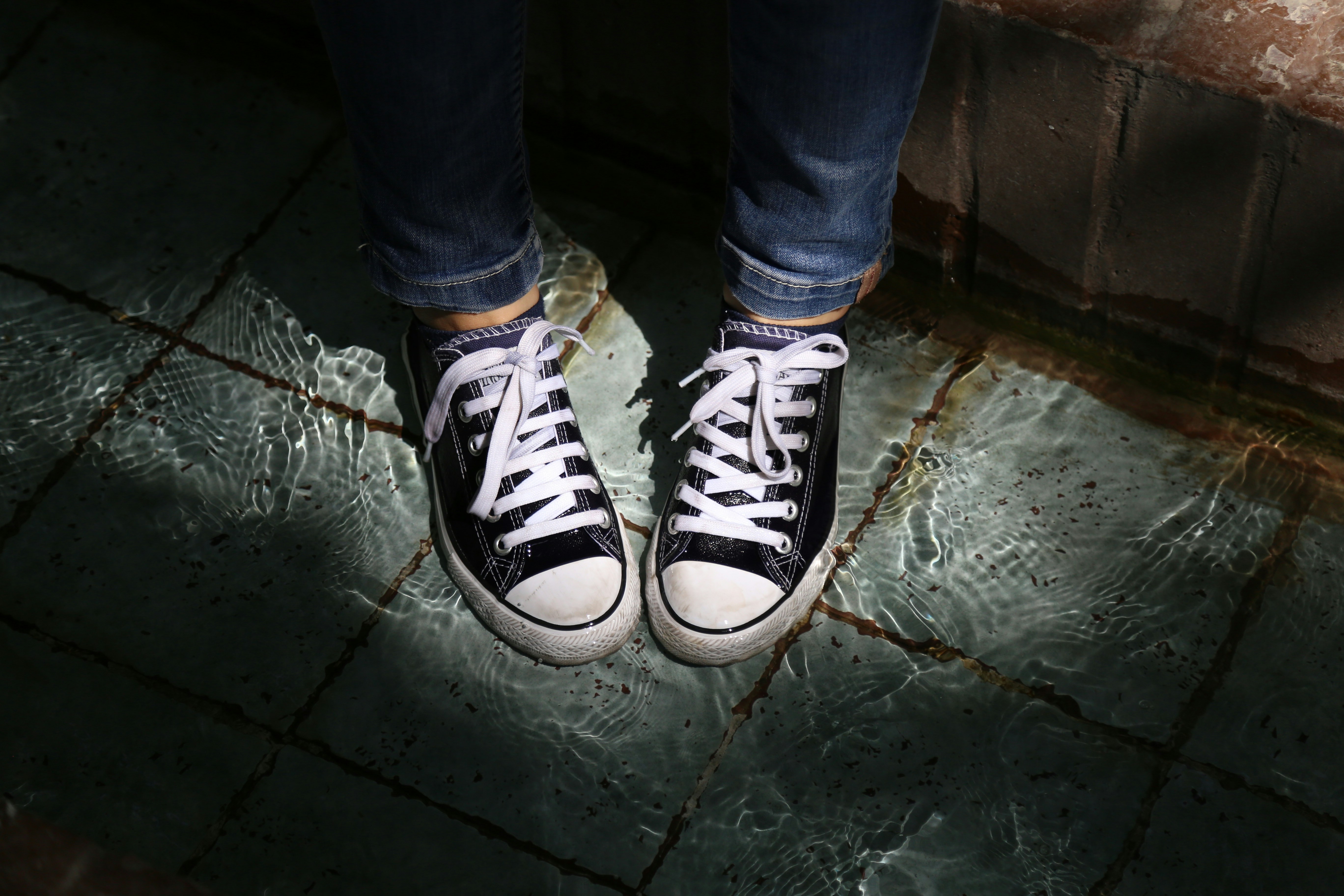 person in blue denim jeans and black and white sneakers