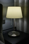 Elegant bedside table in the deluxe room with a warm gold lamp casting a gentle glow.