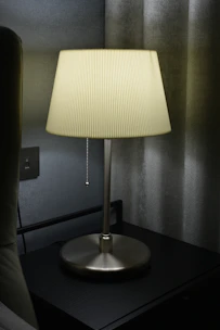 A handcrafted ceramic table lamp with a textured finish illuminating a bedside.