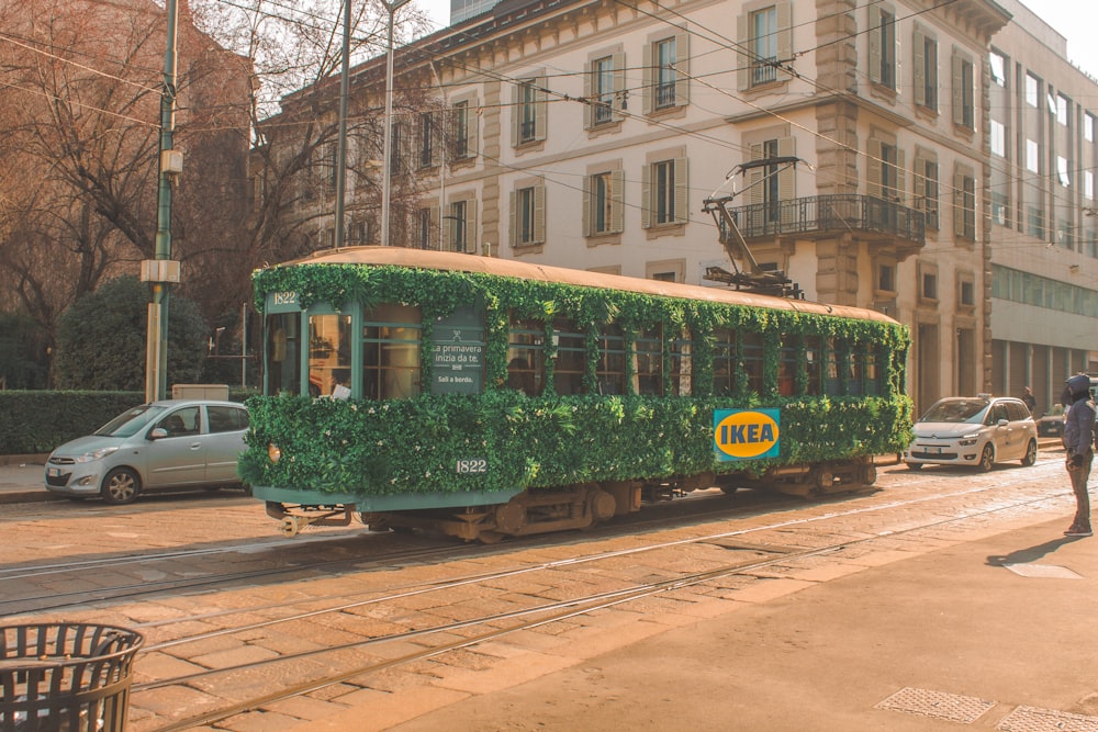 green and yellow train on rail road near building during daytime